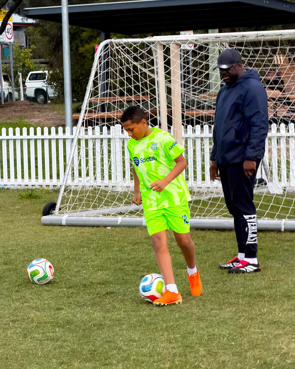Coach watching a player practice dribbling near the goal